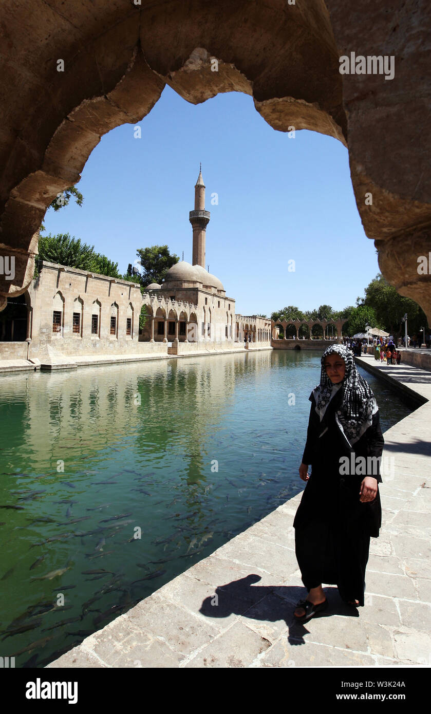 A lady walks next to Balikli Gol (Abraham`s Pool), Golbasi Park in Sanliurfa. In the background stands the magnificent Rizvaniye Vakfi Camii (mosque). Stock Photo
